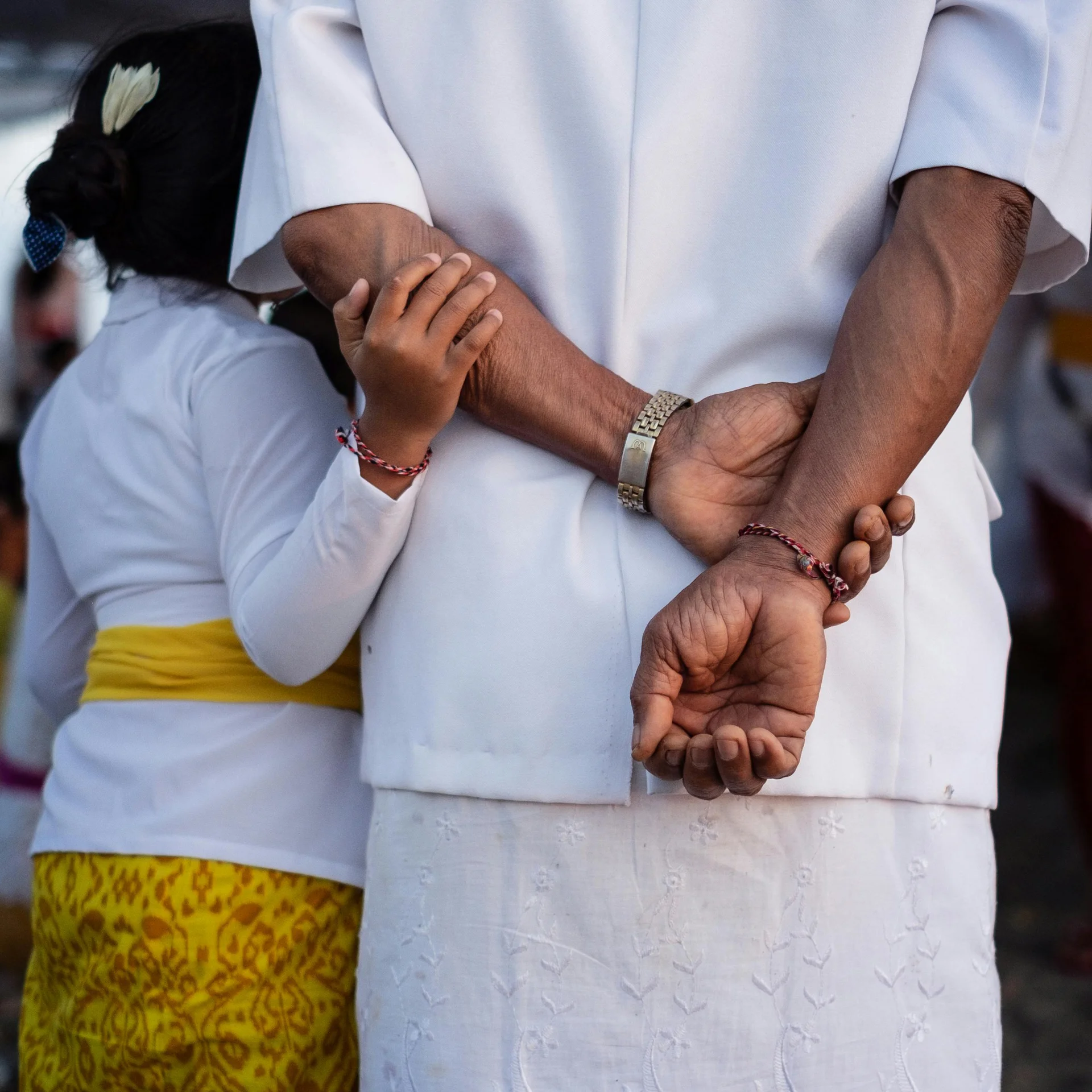 Young child embracing their family member, from behind.