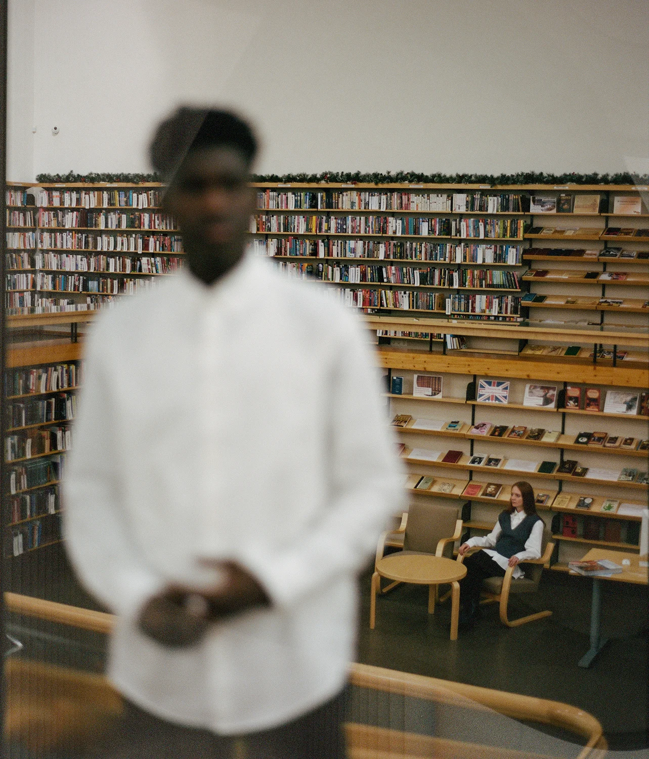 Black man, out of focus, standing in a library
